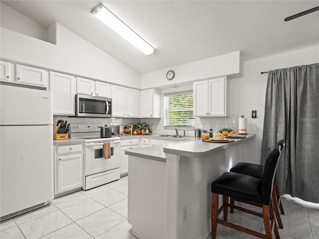 30 N Kaufman Ter, Inverness, FL 34453 - kitchen featuring white cabinets, white appliances, a peninsula, backsplash, and vaulted ceiling