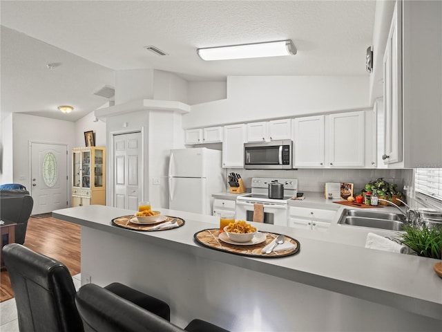 30 N Kaufman Ter, Inverness, FL 34453 - kitchen with a peninsula, white appliances, a kitchen breakfast bar, a sink, and vaulted ceiling