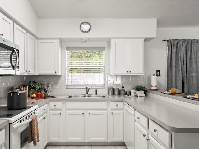 30 N Kaufman Ter, Inverness, FL 34453 - kitchen with decorative backsplash, a peninsula, white appliances, white cabinets, and a sink