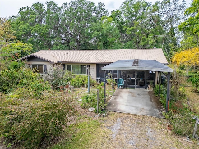 ranch-style home with driveway, metal roof, and a detached carport