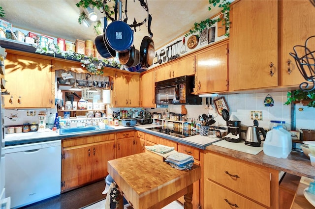 kitchen with brown cabinetry, decorative backsplash, a sink, and black appliances