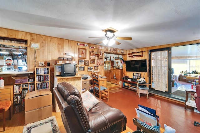 living area with a ceiling fan and wooden walls