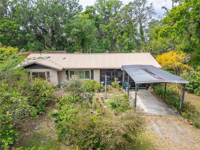 ranch-style house with an attached carport, metal roof, and dirt driveway