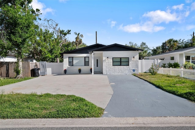 view of front of house featuring driveway, a front lawn, and fence