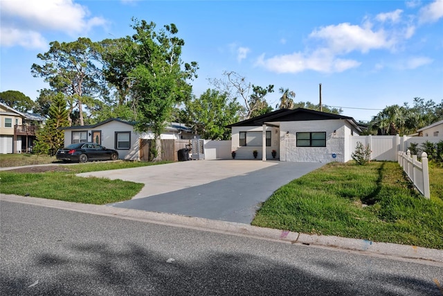 view of front facade featuring concrete driveway, a front lawn, and fence