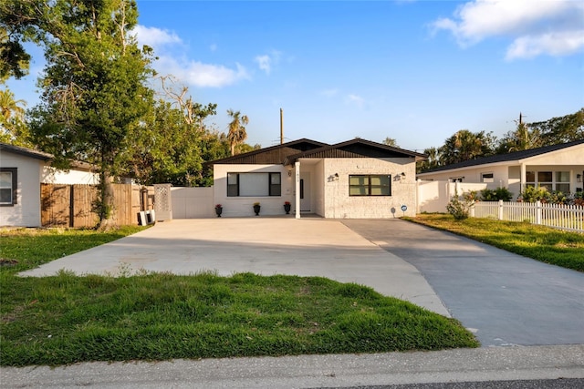 bungalow featuring driveway, a front lawn, and fence