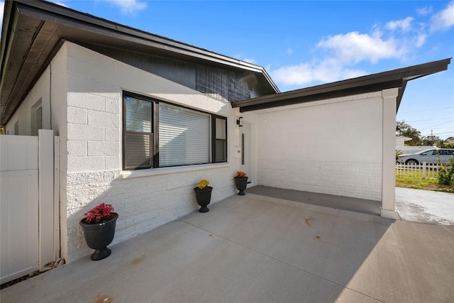 view of property exterior featuring fence, concrete block siding, and a patio