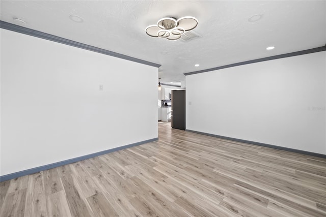 empty room featuring light wood-type flooring, baseboards, recessed lighting, visible vents, and crown molding