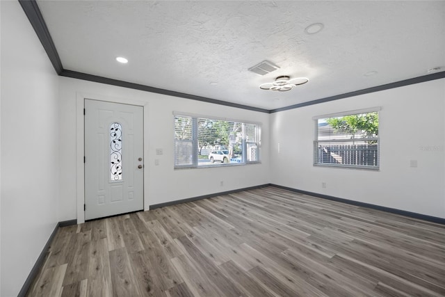 entryway with wood finished floors, visible vents, a wealth of natural light, and crown molding