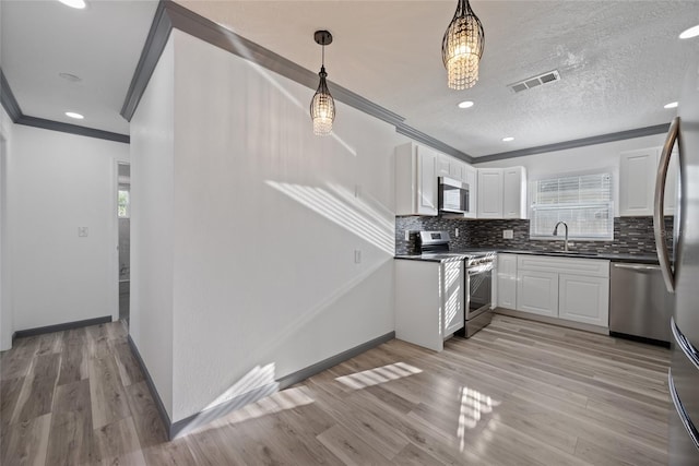 kitchen with crown molding, dark countertops, stainless steel appliances, and a sink