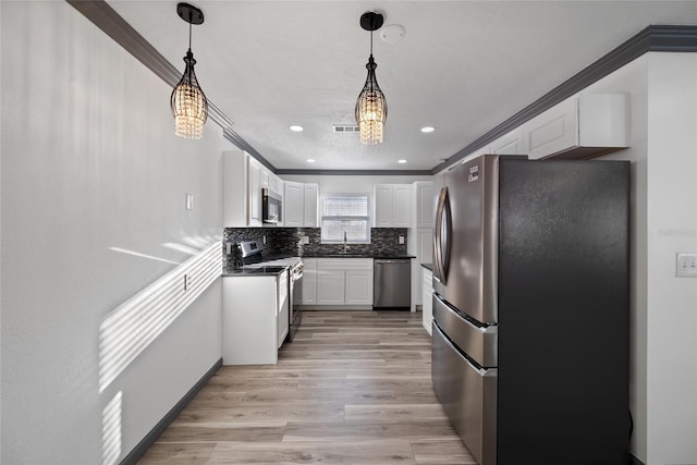 kitchen featuring light wood finished floors, stainless steel appliances, dark countertops, a sink, and white cabinetry