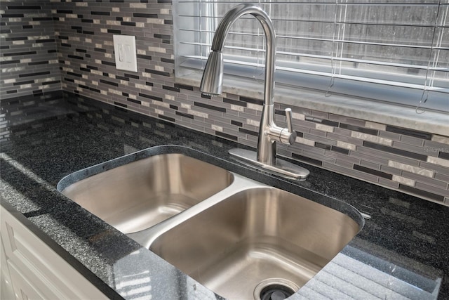 room details with decorative backsplash, a sink, and dark stone countertops