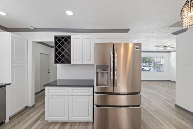 kitchen with white cabinets, appliances with stainless steel finishes, a textured ceiling, and light wood-style flooring