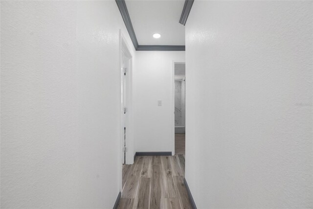corridor featuring baseboards, wood finished floors, and crown molding