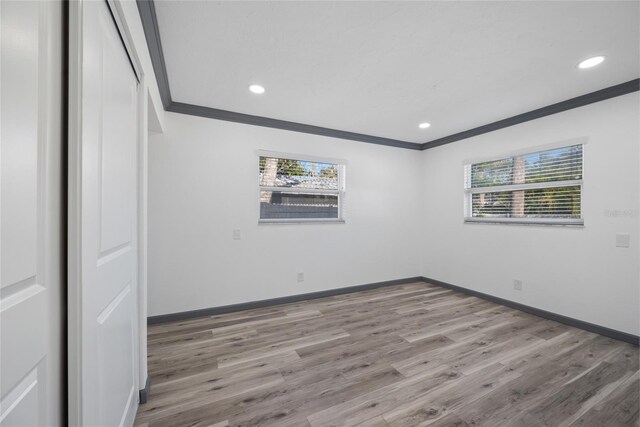 unfurnished room featuring baseboards, crown molding, wood finished floors, and recessed lighting