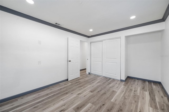 unfurnished bedroom with light wood finished floors, visible vents, a closet, crown molding, and baseboards