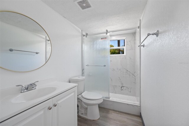 full bath featuring a textured ceiling, toilet, a stall shower, visible vents, and wood finished floors