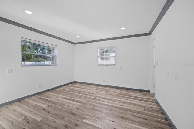 empty room with baseboards, wood finished floors, a healthy amount of sunlight, and crown molding