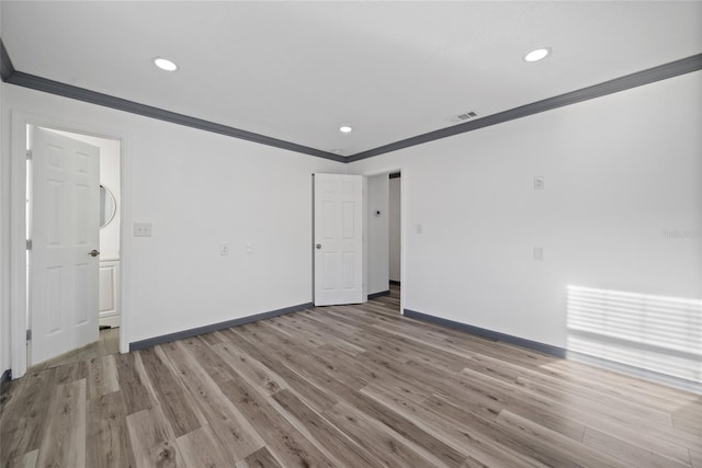 spare room with light wood finished floors, baseboards, ornamental molding, visible vents, and recessed lighting