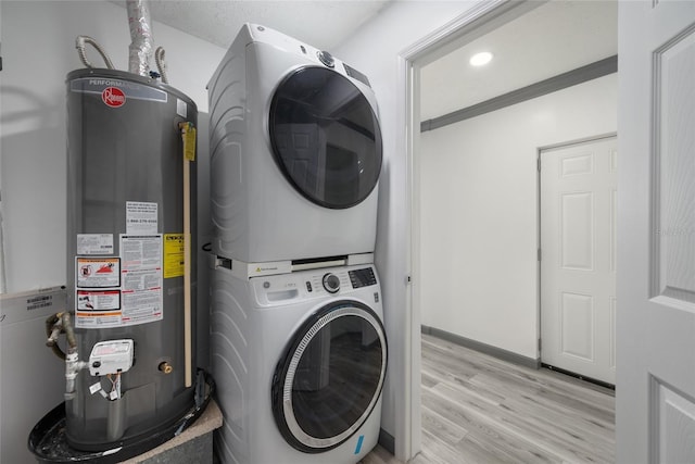 laundry room with stacked washing maching and dryer, gas water heater, light wood-style flooring, and laundry area