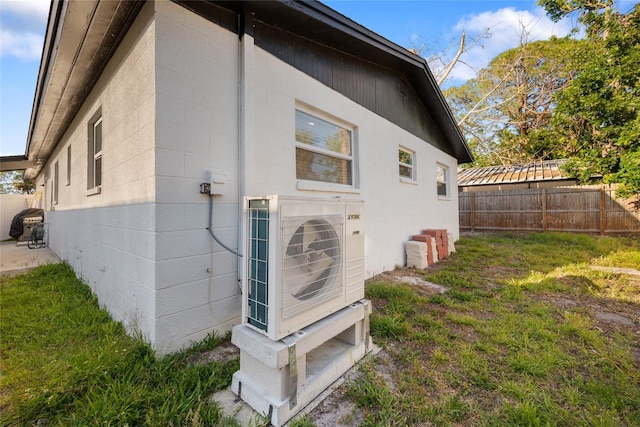 view of home's exterior with fence, concrete block siding, and ac unit