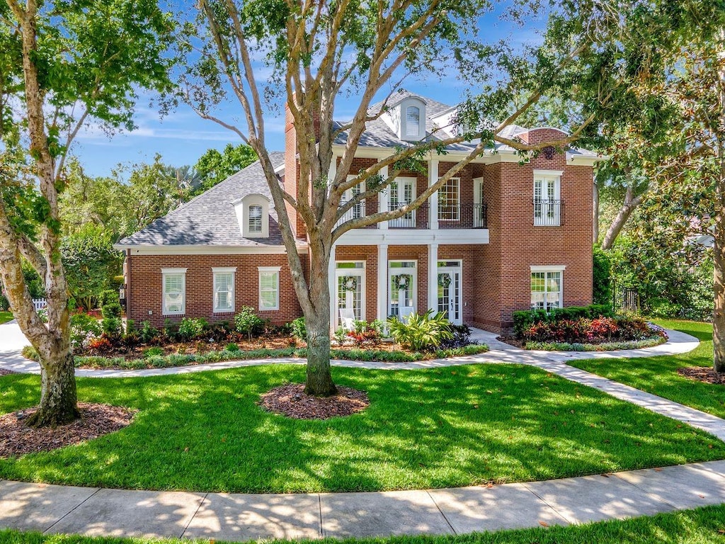 view of front of property with french doors, a front lawn, and brick siding