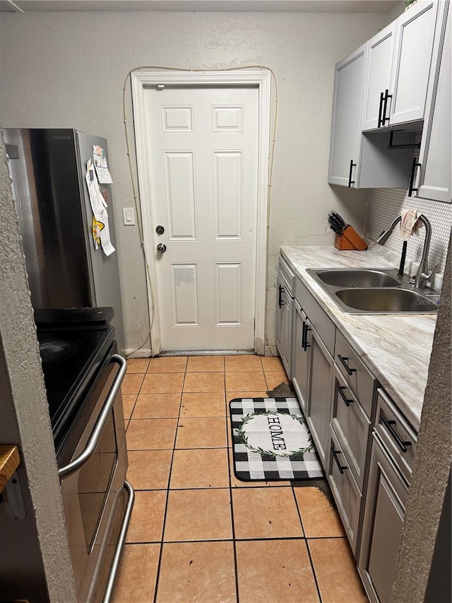 1407 College Park Ln, Tampa, FL 33612 - kitchen featuring light countertops, light tile patterned floors, a sink, freestanding refrigerator, and range