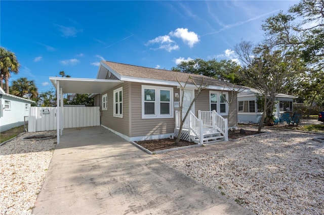 view of front of house with concrete driveway, an attached carport, and fence