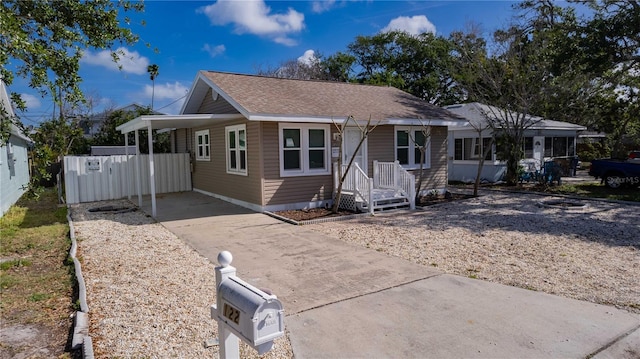 bungalow-style house with fence, a carport, and driveway