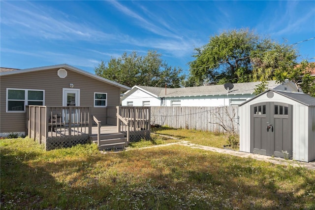 view of yard with an outbuilding, a storage shed, a deck, and fence