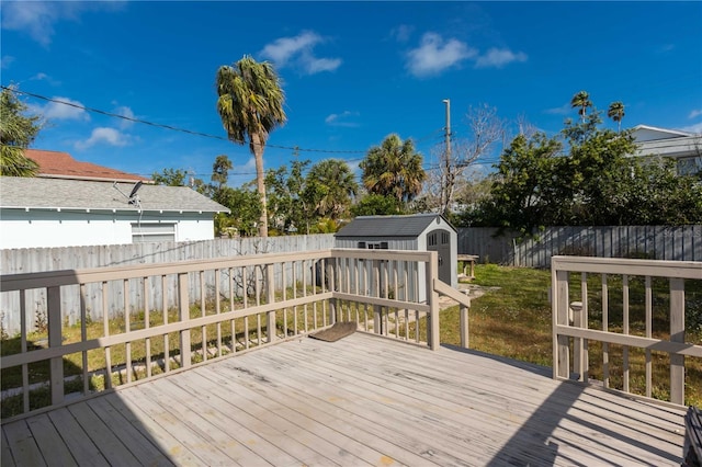 wooden terrace with a fenced backyard, a shed, and an outbuilding