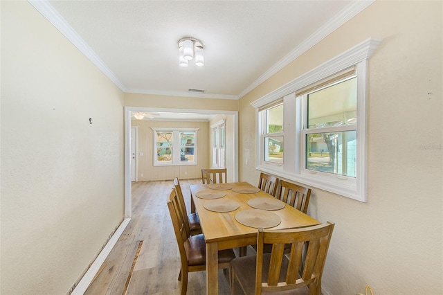 dining space with visible vents, ornamental molding, and wood finished floors