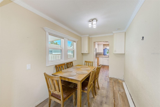 dining space featuring ornamental molding and light wood-style flooring