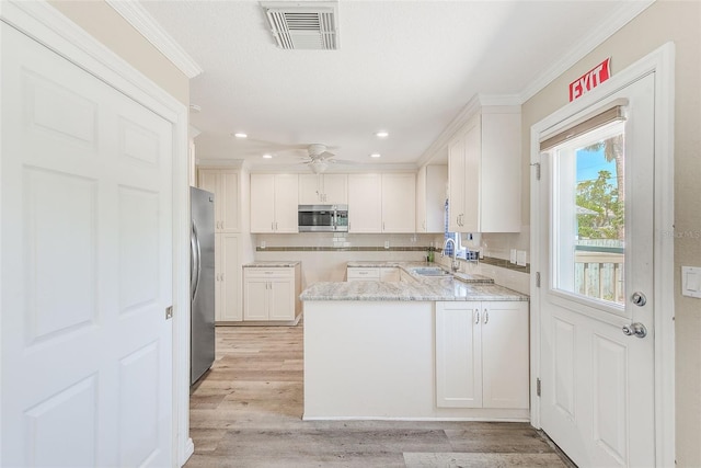 kitchen with ornamental molding, visible vents, a peninsula, and stainless steel appliances