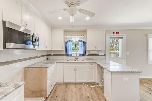 kitchen with stainless steel microwave, a sink, a peninsula, and a healthy amount of sunlight