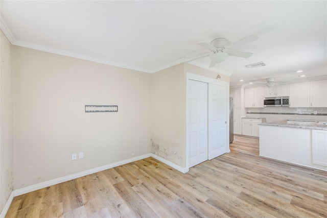kitchen with stainless steel microwave, ceiling fan, crown molding, visible vents, and baseboards