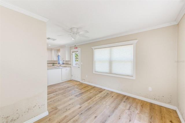 interior space featuring ornamental molding, a ceiling fan, light wood-style flooring, and baseboards