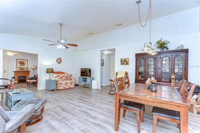 5906 Greenbriar Ct, Zephyrhills, FL 33542 - dining area featuring light wood-type flooring, a ceiling fan, visible vents, a glass covered fireplace, and baseboards