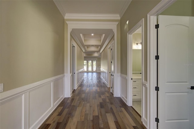 corridor with dark wood-type flooring, ornamental molding, a decorative wall, and a wainscoted wall