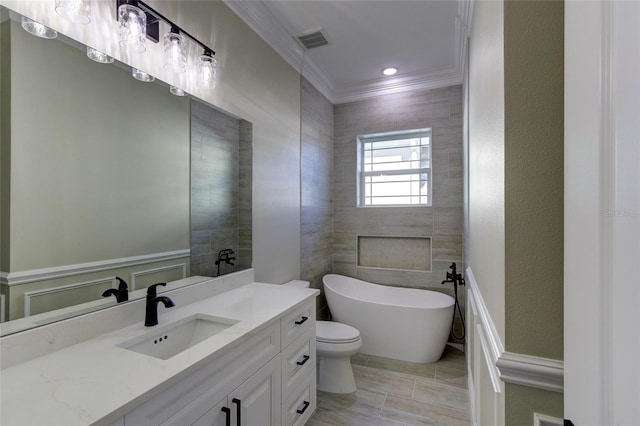 full bath featuring crown molding, vanity, toilet, a freestanding tub, and visible vents