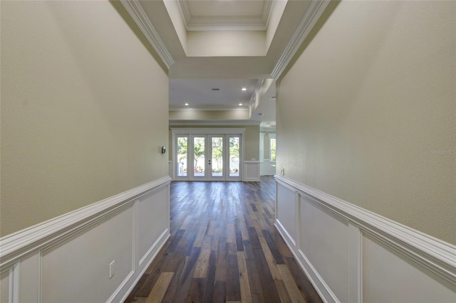 hall featuring a decorative wall, a tray ceiling, and dark wood-type flooring