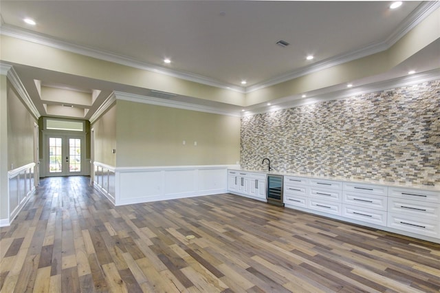 interior space featuring a decorative wall, beverage cooler, a wainscoted wall, french doors, and dark wood finished floors