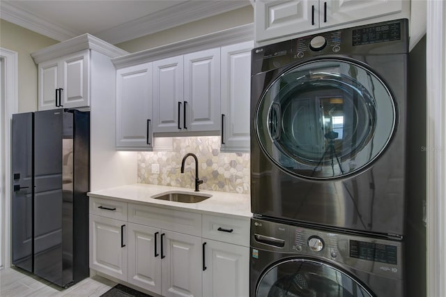 laundry room featuring cabinet space, stacked washer and dryer, ornamental molding, and a sink