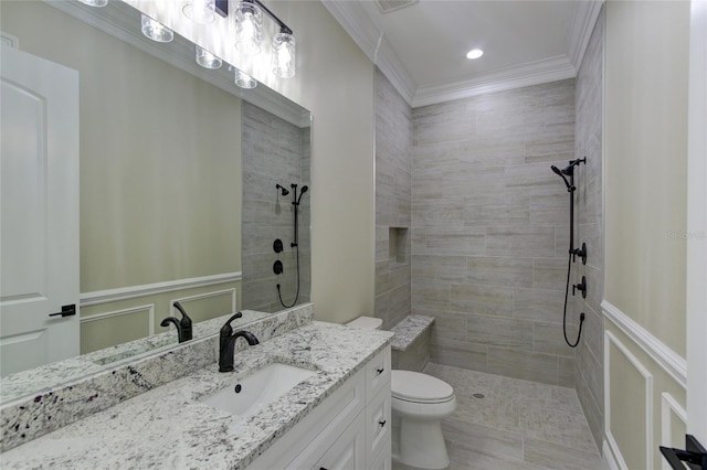 full bath with vanity, ornamental molding, a tile shower, and toilet