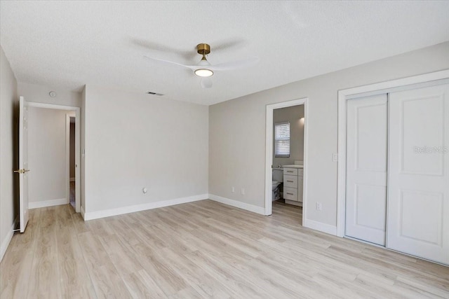3404 33rd Street Ct W, Bradenton, FL 34205 - unfurnished bedroom featuring light wood finished floors, a closet, ensuite bath, baseboards, and a textured ceiling