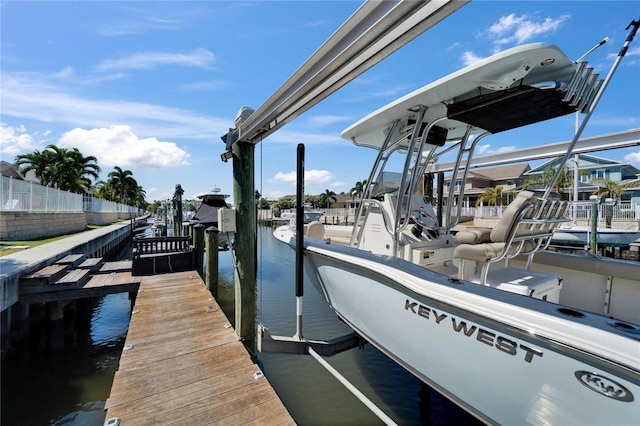 view of dock with a water view, fence, and boat lift