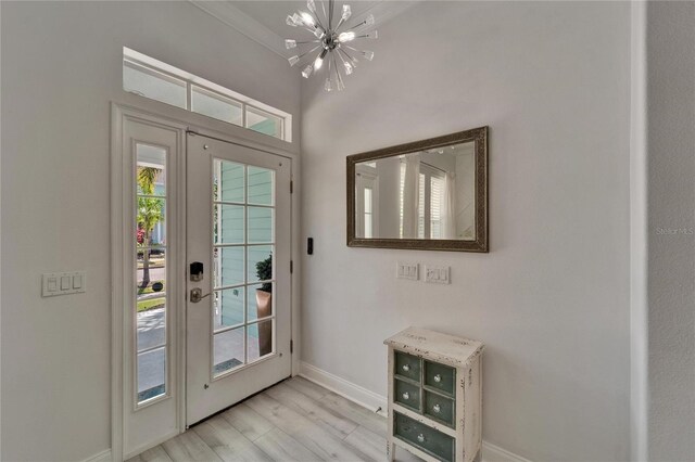 entryway featuring baseboards, a chandelier, and light wood-style floors
