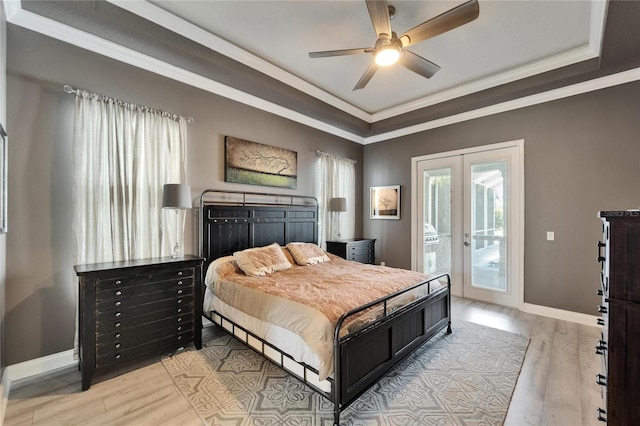 bedroom with access to outside, a tray ceiling, ornamental molding, french doors, and light wood finished floors