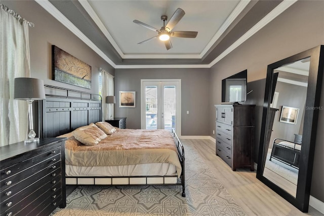 bedroom featuring a tray ceiling, ornamental molding, french doors, light wood finished floors, and baseboards