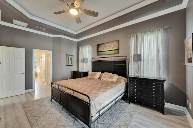 bedroom featuring visible vents, baseboards, crown molding, a tray ceiling, and wood finished floors